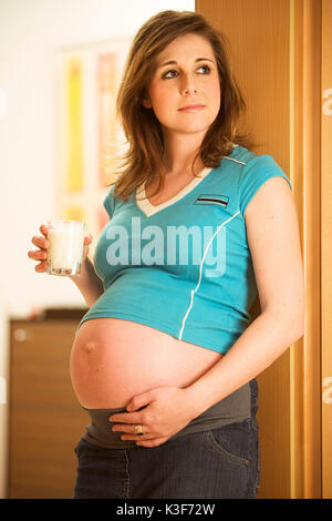 Pregnant young woman holds a glass of milk in the hand Stock Photo
