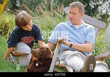 Father and son with dog in the garden Stock Photo