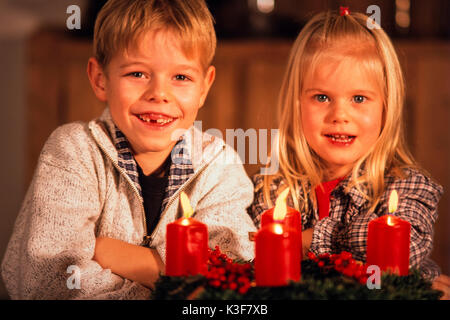 Two children while an Advent wreath in him all four candles burn Stock Photo
