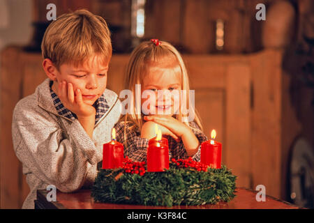 Two children while an Advent wreath where all four candles burn Stock Photo