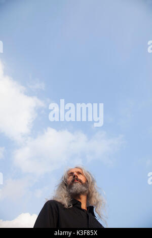 Low Angle View Portrait of Contemplative Mid-Adult Man with Beard and Long Hair Stock Photo