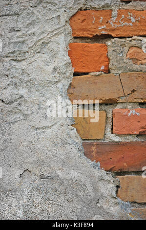 Red bricks stone wall background closeup, cracked ruined stucco, vertical plastered grunge grey beige stonewall limestone pattern, old aged weathered  Stock Photo