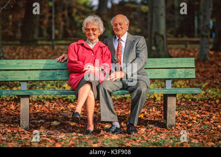 Senior citizen's couple sits together on a wooden bench at the wood Stock Photo