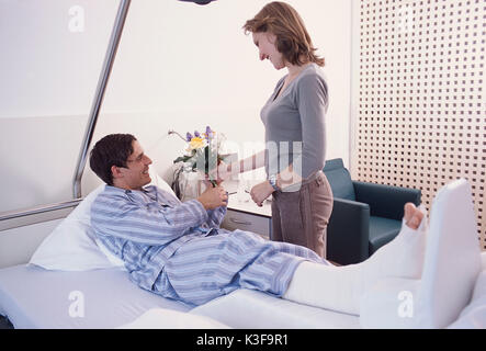 Young woman attends man with broken foot at the hospital Stock Photo