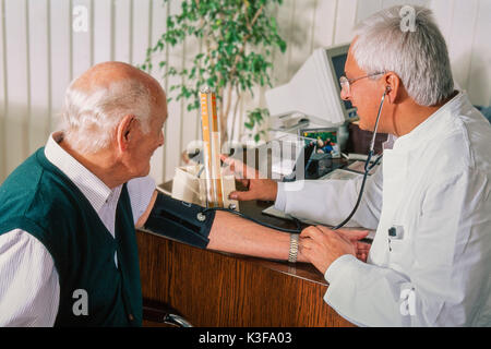 Doctor measures to an old man the blood pressure Stock Photo