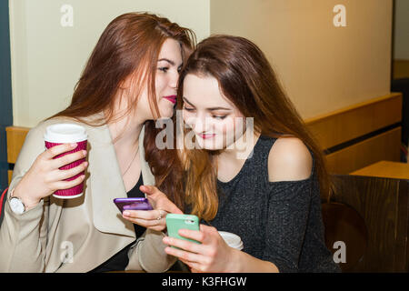 Two girls gossiping in a cafe bar Stock Photo