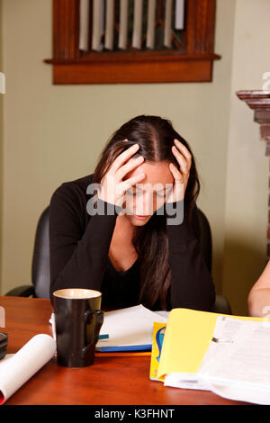 Young woman puts head in hands, stressed and upset at work. Stock Photo