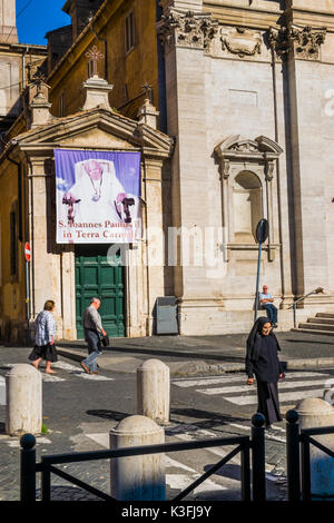 street scene in front of santa maria in traspontina church with banner showing pope john paul II and a nun crossing the street Stock Photo