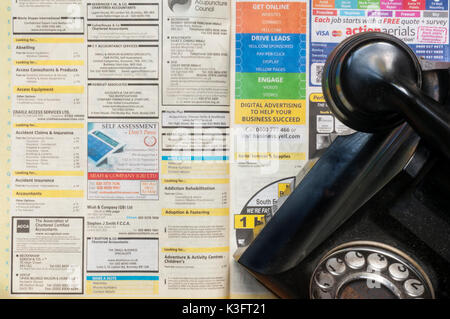 An old telephone on a copy of Yellow Pages which are to stop publishing in printed form in 2018 Stock Photo