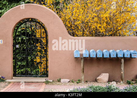 Nine light blue colored mailboxes in front of a Spanish styled courtyard gate Stock Photo