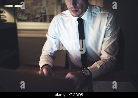 Horizontal crop shot of a lawyer using the laptop sitting at workplace in the evening. Stock Photo
