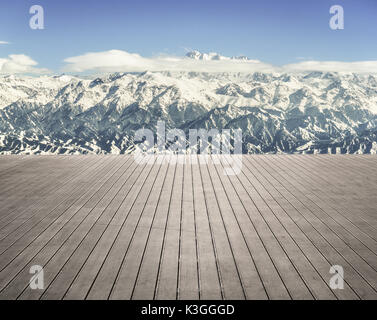 Wooden terrace with snow capped mountains Stock Photo