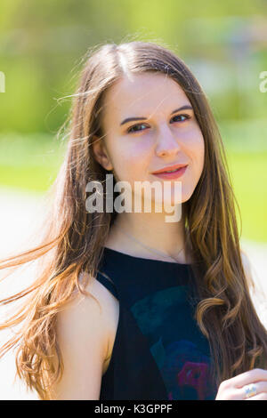 Portrait of young beautiful woman with long hair in green spring park Stock Photo