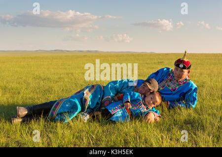 Inner Mongolia, China-July 30, 2017: Nomadic Mongolian family with their traditional colorful dresses near their yurt in immense grassland of the coun Stock Photo