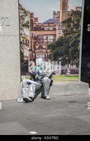 SYDNEY,NSW,AUSTRALIA-NOVEMBER 20,2016: Silver costumed street busker reading in solitude at the Circular Quay in Sydney, Australia Stock Photo