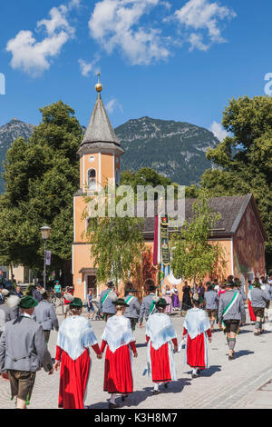 Germany, Bavaria, Garmisch-Partenkirchen, Bavarian Festival, Group in Traditional Costume Marching and Church Stock Photo