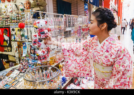 Japan, Hoshu, Tokyo, Asakusa, Nakamise Shopping Street, Girl in Kimono Buying Souvenirs Stock Photo