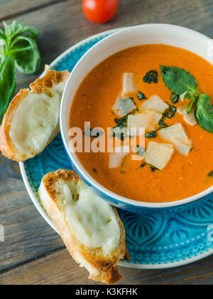 Fresh tomato soup with baked cheese Ciabatta on a wooden table, top view Stock Photo