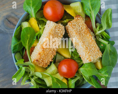 Baked feta cheese in sesame crust on mixed salad with mango