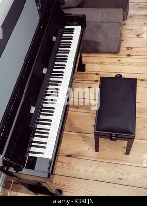 High angle view of a black piano with a piano stool on a wooden ground Stock Photo