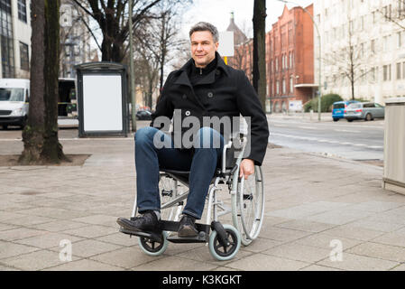 Portrait Of A Smiling Disabled Man On Wheelchair In City Stock Photo