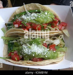 Two veggie tacos filled with guacamole, tomatoes, shredded lettuce, onion, chives, topped in parmesan cheese Stock Photo