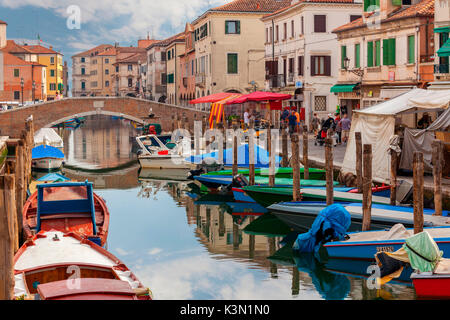 Chioggia. Boats moored in the channel and the local market on the way. Veneto, Venice, Italy Stock Photo