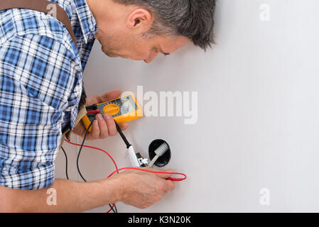 Close-up Of A Male Technician Checking Socket With Multimeter Stock Photo