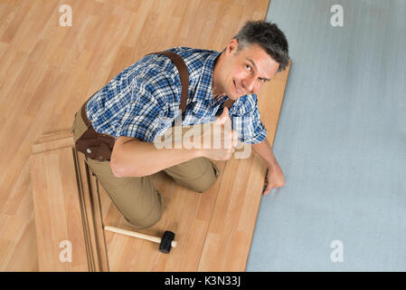 High Angle View Of A Smiling Worker Assembling New Laminate Floor Stock Photo