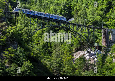 Vigezzina train passes over a steel bridge in Camedo, Borgnone, Canton Ticino, Switzerland Stock Photo