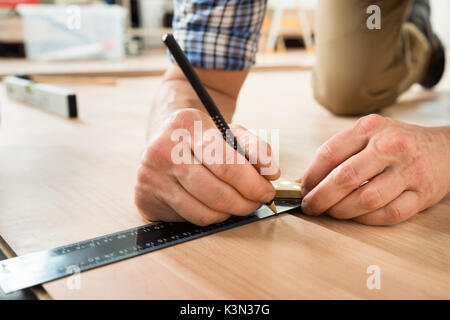 Close-up Of A Worker Drawing A Mark On Laminate Using Ruler Stock Photo
