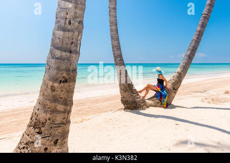 Juanillo Beach (playa Juanillo), Punta Cana, Dominican Republic. Woman under high palm trees on the beach (MR) Stock Photo