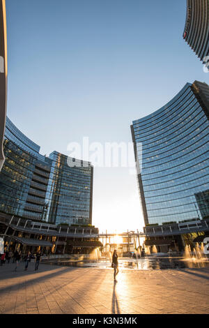Milan, Lombardy, Italy. People walking in Gae Aulenti square in the Porta Nuova business district at sunset. Stock Photo