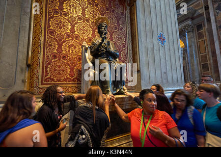 Pilgrims touching the foot of Saint Peter Enthroned in the St. Peter's Basilica, Vatican City, Rome, Italy Stock Photo