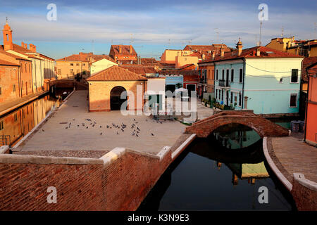 View of Comacchio village at sunrise from the Trepponti bridge, with houses reflected in the canals. Province of Ferrara, Emilia Romagna, Italy Stock Photo