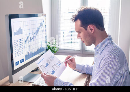 Trader analyzing financial report and trading charts and computer screen for successful sell buy strategy of stock market investment, fintech concept Stock Photo