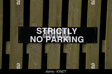 A 'Strictly No Parking' sign is attached to a wooden fence Stock Photo
