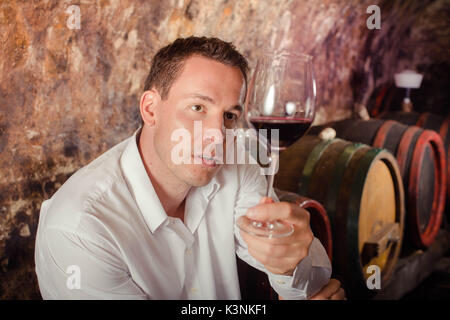 man having wine tasting in cellar Stock Photo