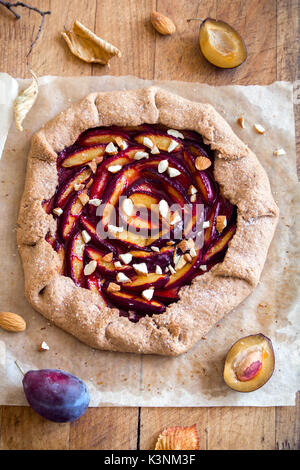 Plum Galette. Healthy homemade wholegrain fruit pie (galette) with plums, almonds and brown sugar, vegan vegetarian autumn dessert food. Stock Photo