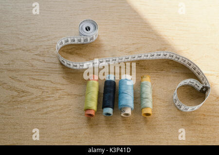 Sewing still life - different color cotton thread spools, thimble, needle, measuring tape Stock Photo