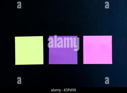 Three multi colored blank sticky note on black background Stock Photo