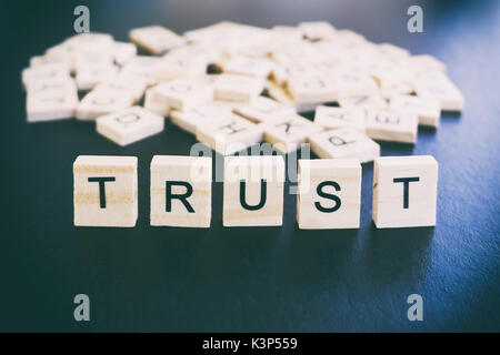 Trust words on a wood blocks, focus on the foreground with filter and analog effect Stock Photo