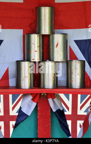 a fairground stall at a fete with tin cans that need to be knocked down by throwing balls at them coconut shy fairground attractions games of skill Stock Photo