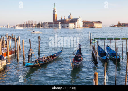 Two gondolas with tourists at sunset enterig Rio Palazzo o de Canonica, San Marco, Venice in front of the Doges Palace with a view over the lagoon to  Stock Photo