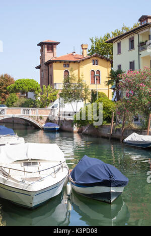 Canal with colorful yellow Liberty style Villa and moored boats, Lido, Venice, Veneto,  Italy. Lido is popular with  Venetians as a summer resort and  Stock Photo
