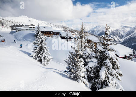 Skiers frame the typical alpine village immersed in snow Bettmeralp district of Raron canton of Valais Switzerland Europe Stock Photo