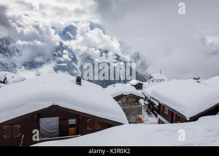 Clouds frame the mountain huts covered with snow Bettmeralp district of Raron canton of Valais Switzerland Europe Stock Photo