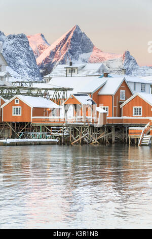 The colors of dawn frames the fishermen houses surrounded by snowy peaks Sakrisøy Reine Nordland Lofoten Islands Norway Europe Stock Photo