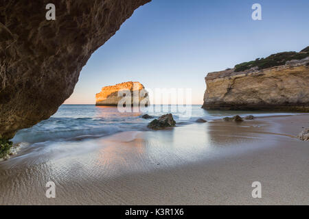 A sea cave frames the beach of Praia De Albandeira at dawn Carvoeiro Caramujeira Lagoa Municipality Algarve Portugal Europe Stock Photo