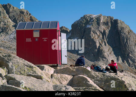 Hikers resting at the entrance of the bivouac Molteni Valsecchi makeshift shelter for trekkers who venture on these  peaks. Valmasino. Valtellina. Lombardy Italy Europe Stock Photo